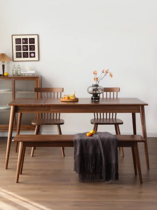 Mid century modern extendable dining table in solid walnut styled with bench seating and spindle-back chairs