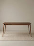 Studio view of the rectangular extendable dining table in solid American walnut with clean minimalist styling