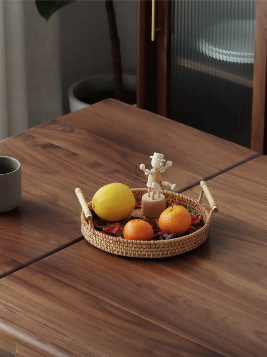 Close-up of the walnut dining table surface with visible natural grain and extension line beside a woven tray
