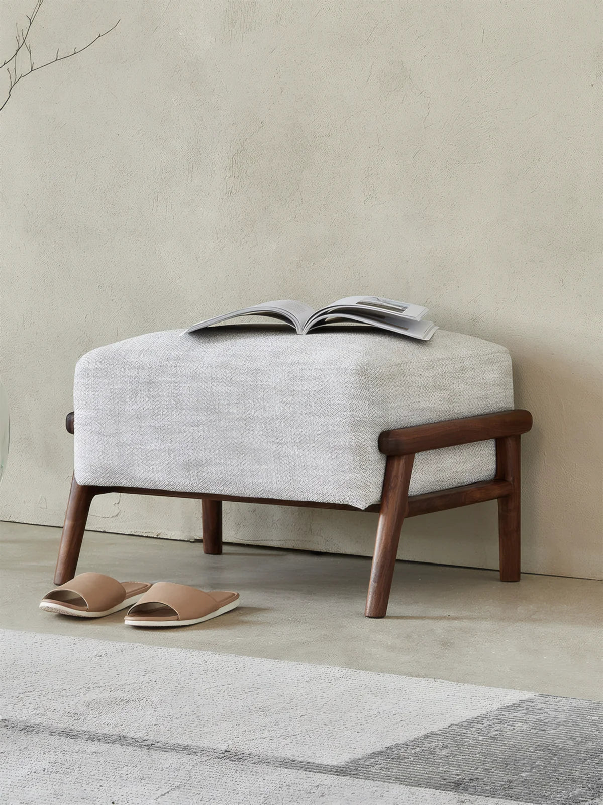 Walnutry Heritage Footstool side angle view, upholstered fabric footstool with walnut wood frame in a calm mid century living space