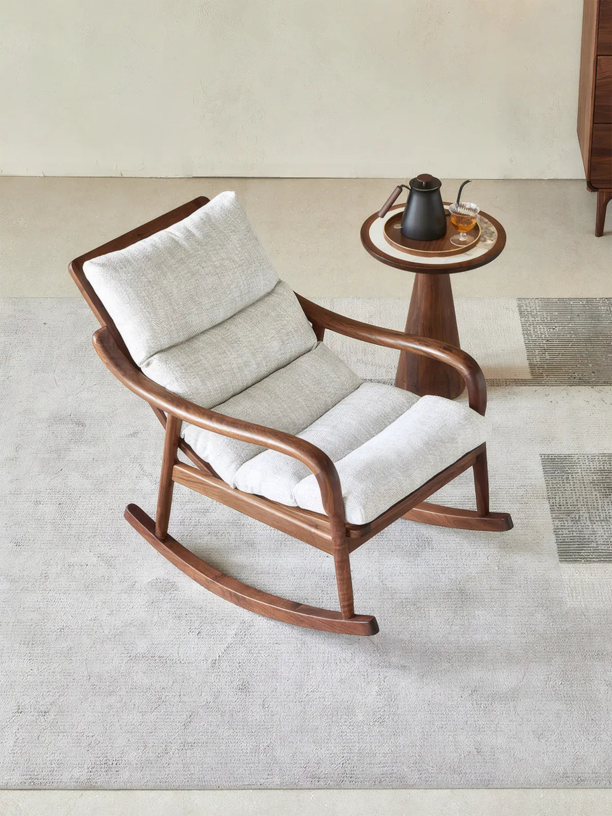 Walnutry Heritage Rocking Lounge Chair top angle lifestyle view, upholstered walnut lounge chair placed beside a small round side table in a serene interior