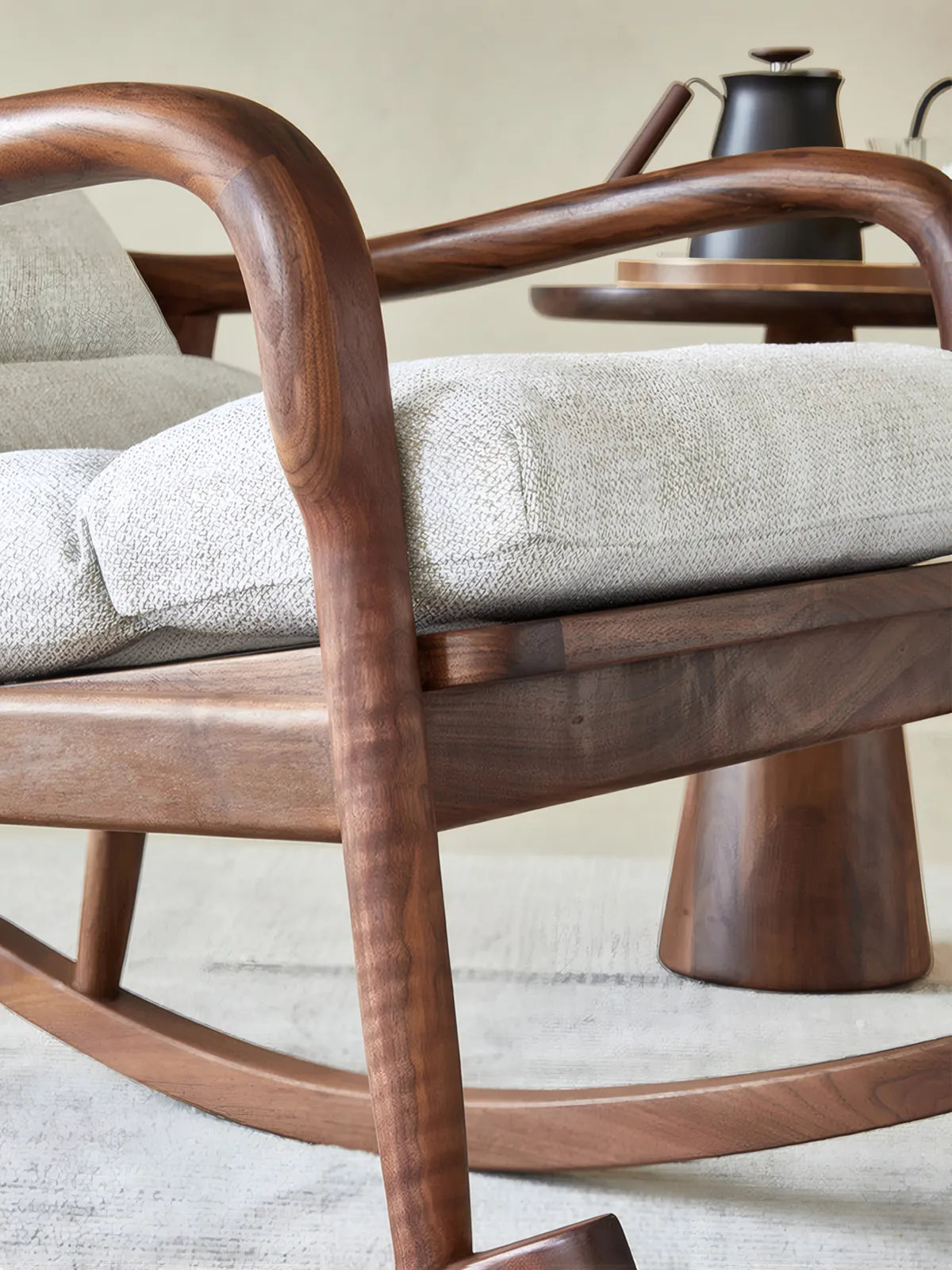 Walnutry Heritage Rocking Lounge Chair close-up showing sculpted walnut armrest, solid wood frame detail, and upholstered seat cushion in a vintage inspired lounge setting