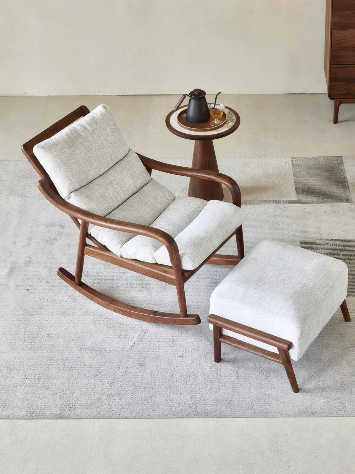 Walnutry Heritage Rocking Lounge Chair in walnut with matching ottoman, styled in a calm mid century modern living room with side table for relaxed reading and lounging