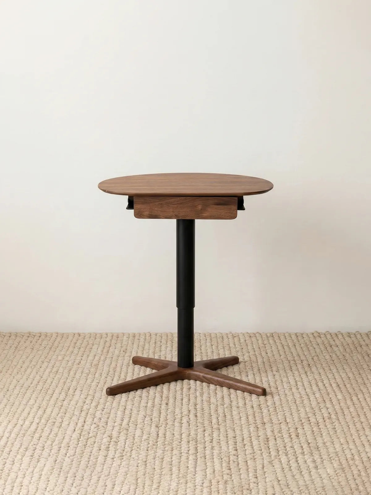 Full frontal view of The Heritage Adjustable Side Table showcasing its premium solid walnut top, sleek black center post, and cross-shaped wood base.