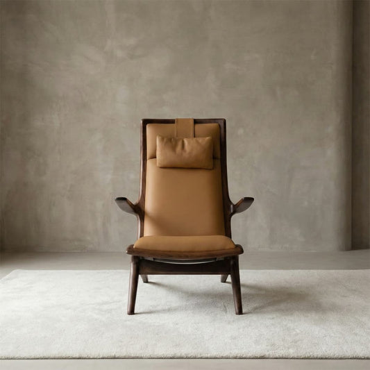 Sculptural high-back lounge chair in tan genuine leather with a headrest pillow, featuring a unique architectural solid walnut frame.