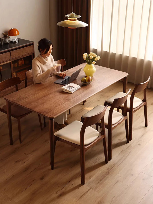 A woman comfortably working on her laptop while seated in the Japandi solid wood chair, blending dining and home office functionality.