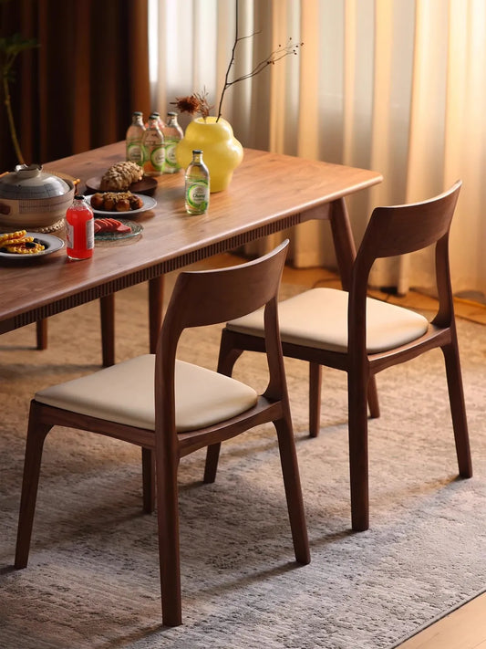 Two Walnutry Japandi solid wood dining chairs crafted from FAS grade black walnut, styled alongside a matching wooden dining table with a casual meal setting.