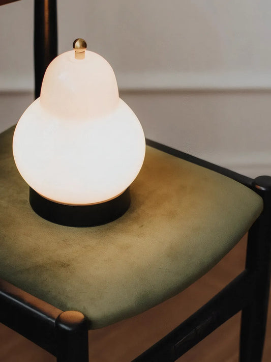 Close-up of the Korin dining chair green velvet seat surface and black frame corner detail with a decorative lamp