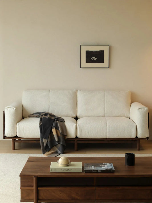 Lior sofa in white fabric styled in a living room with walnut coffee table and framed artwork