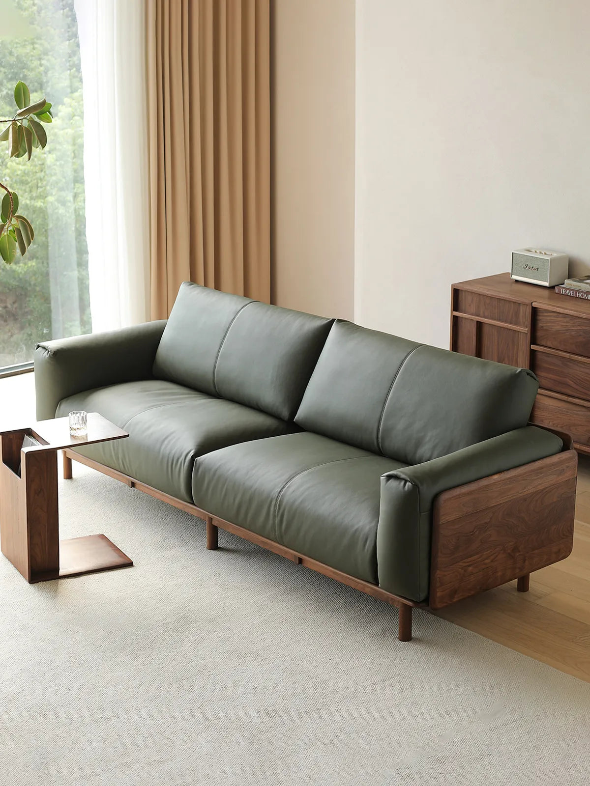 Lior sofa in olive green leather with walnut wide-plank arm panel, three-quarter view in living room (Green)