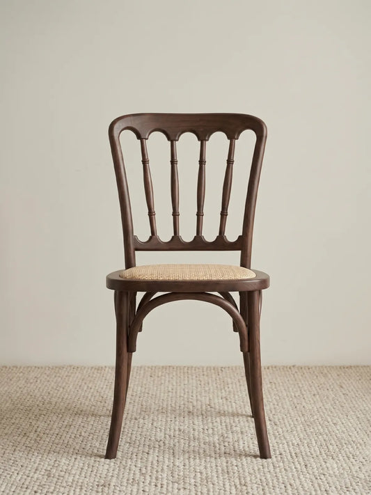 Lovan spindle back dining chair in solid walnut with handwoven rattan seat, front view on neutral rug