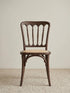 Lovan spindle back dining chair in solid walnut with handwoven rattan seat, front view on neutral rug