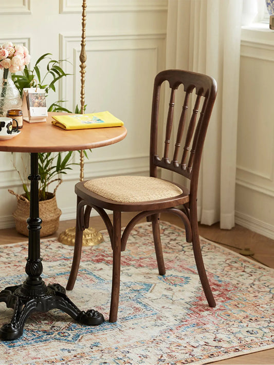 Lovan walnut dining chair with rattan seat in a bright room with white wainscoting and a round bistro table