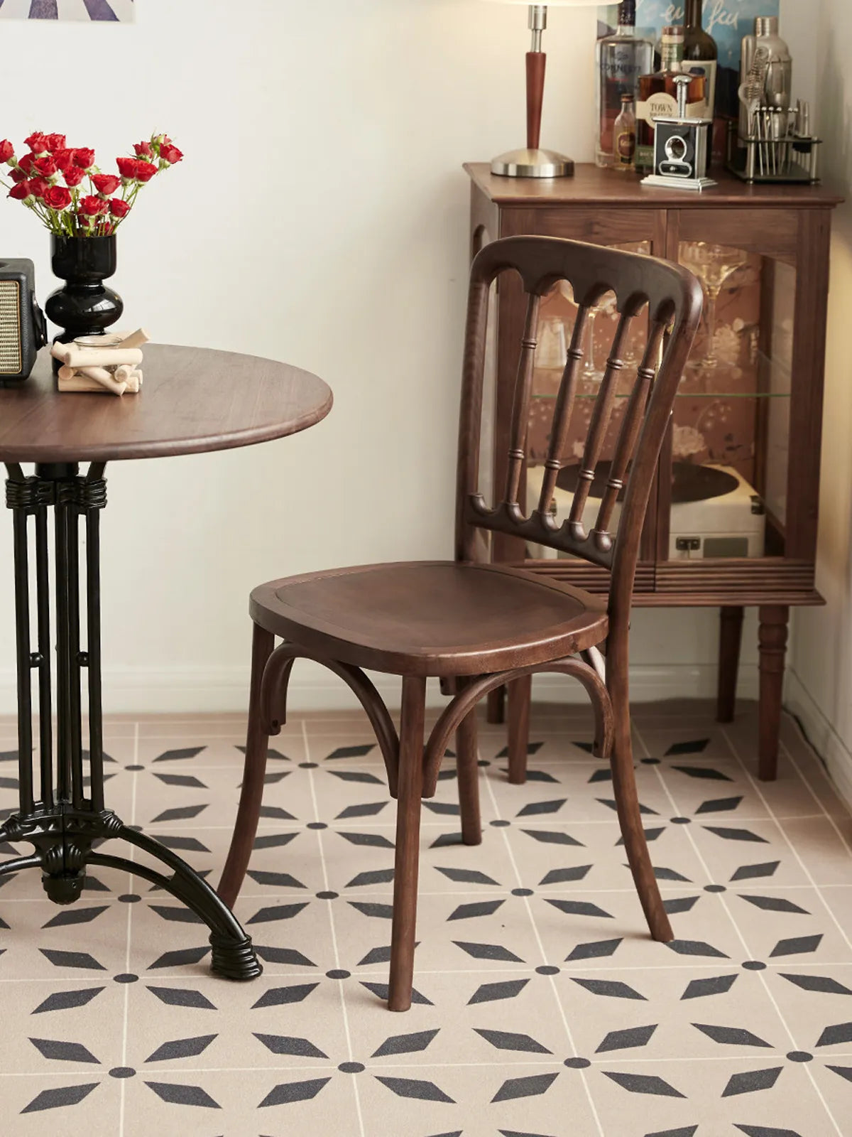 Lovan walnut dining chair seen from the rear three-quarter angle beside a round bistro table on patterned tile floor