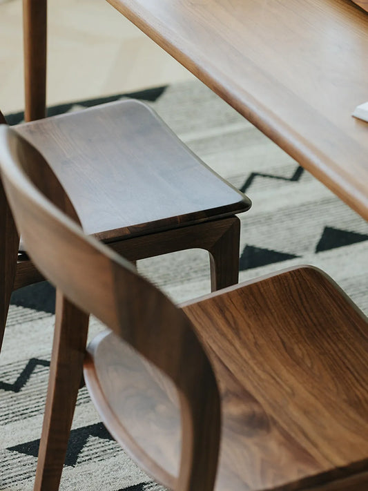 Two Maren walnut dining chairs at a solid walnut dining table in a styled living space with text overlay