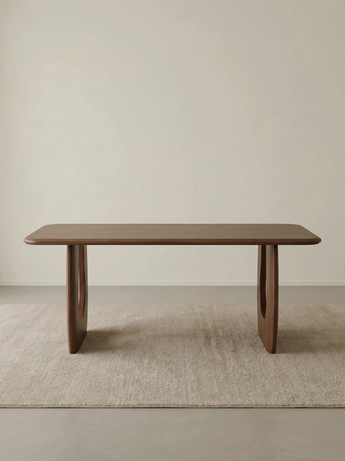 Front studio view of the Marlow walnut dining table centered on a neutral rug.