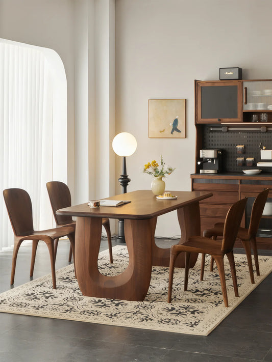Side angle of the Marlow double pedestal dining table in a light-filled dining space with walnut chairs.