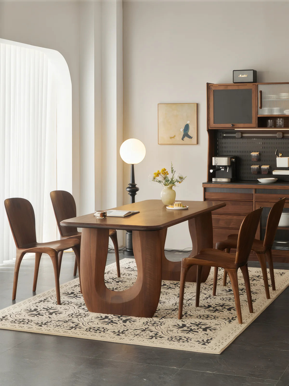 Wide room view of the Marlow dining table in American black walnut with surrounding chairs on a patterned rug.