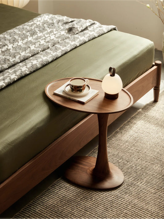 The Orbit table used as narrow mid century modern bedside tables next to a green bed, styled with a modern lamp in a warm bedroom.