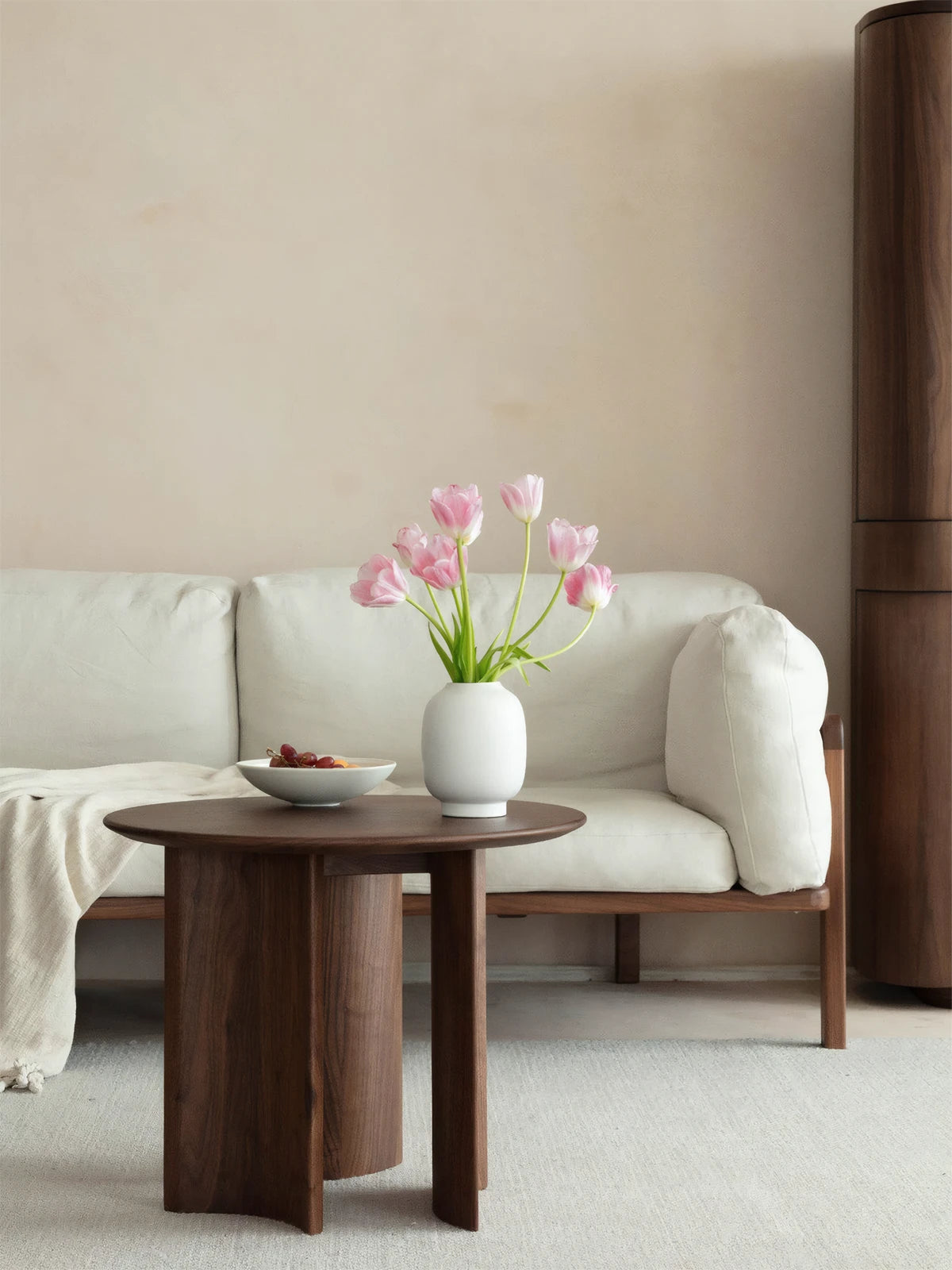 The Cumberland mid century modern round end table styled beautifully next to a cream sofa in a modern organic living room.