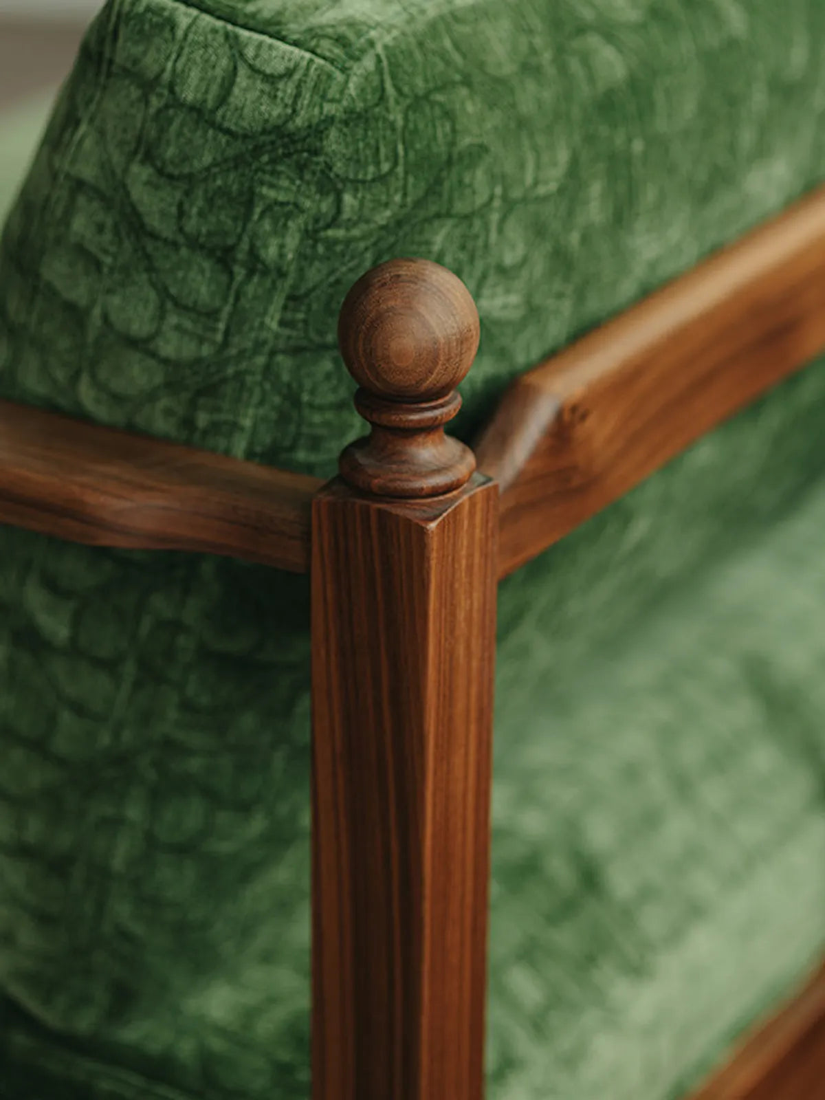 Close-up of the elegant hand-carved spherical finial and the rich, natural wood grain on the corner post of the Morris sofa.