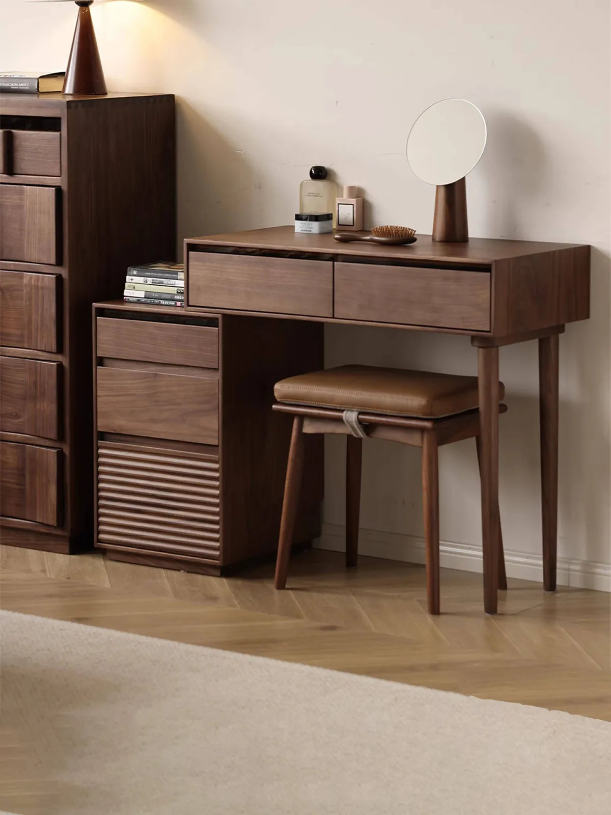 The complete Muse Vanity Desk and Integrated Nightstand set crafted from solid walnut, styled with a matching leather-cushioned stool in a modern bedroom.
