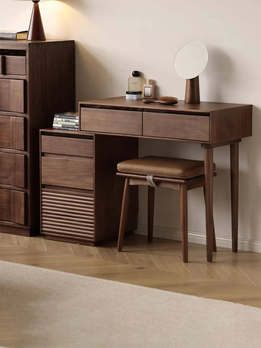 The complete Muse Vanity Desk and Integrated Nightstand set crafted from solid walnut, styled with a matching leather-cushioned stool in a modern bedroom.