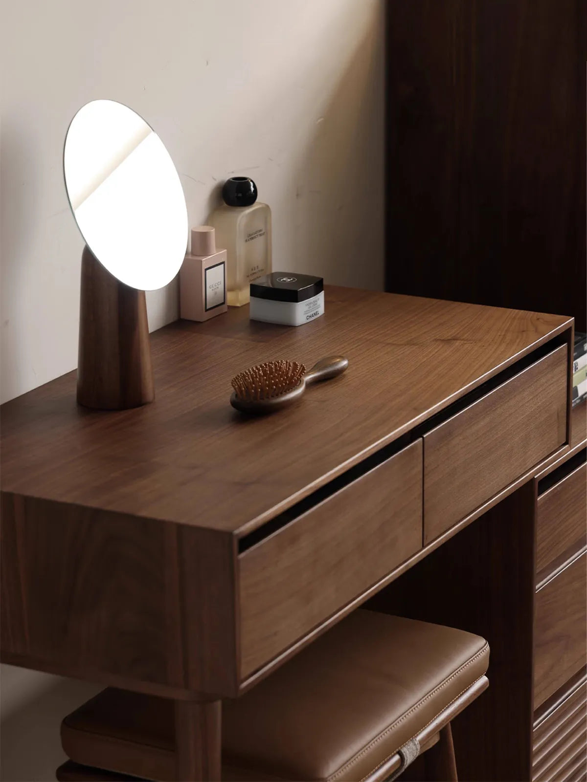 Close-up of the premium North American Black Walnut wood grain on the surface of the Muse Vanity Desk, featuring a wooden comb and perfume.
