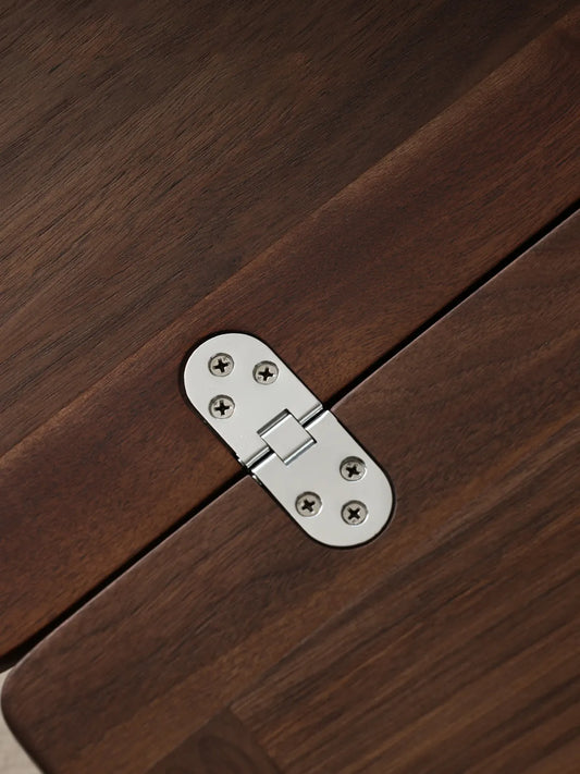 Detailed view of the durable stainless steel hinge connecting the solid black walnut leaves on The Nomad Mobile Folding Side Table.