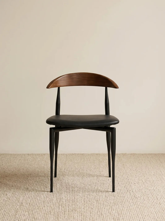 Noren dining chair front view showing curved walnut backrest and black upholstered seat on slender steel legs