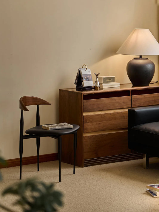 Noren dining chair in a living space beside a walnut dresser with lamp and decor