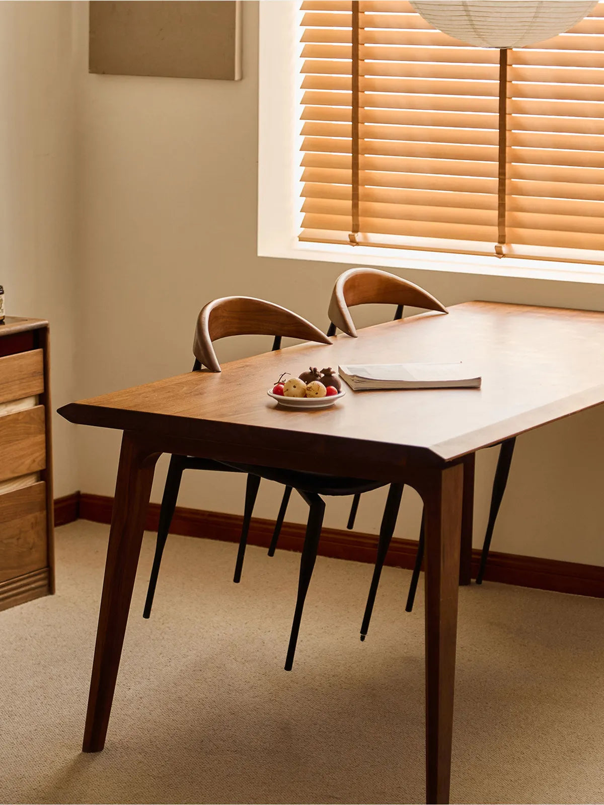 Two Noren dining chairs tucked under a walnut dining table in a warm-lit room with blinds