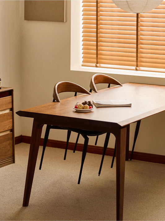 Two Noren dining chairs tucked under a walnut dining table in a warm-lit room with blinds