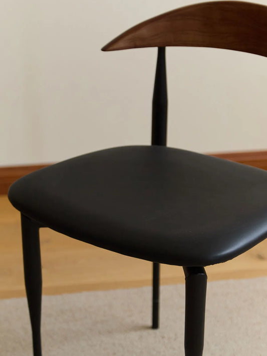 Close-up of the Noren chair padded black upholstered seat and walnut backrest from above