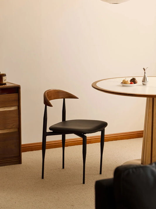 Noren dining chair side profile in a dining room setting with round table and walnut sideboard