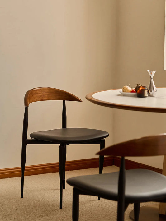 Noren dining chair three-quarter rear view showing curved walnut back and steel frame at a dining table