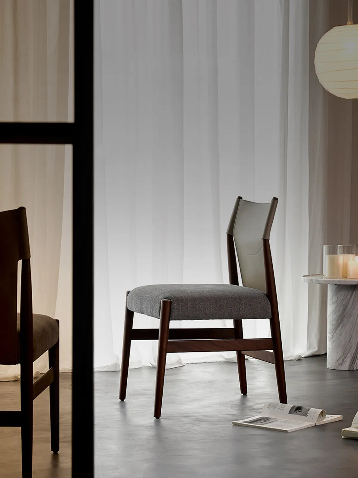 Walnutry Opus Series solid black walnut dining chair front view featuring a curved ergonomic backrest and tapered legs in a modern setting.