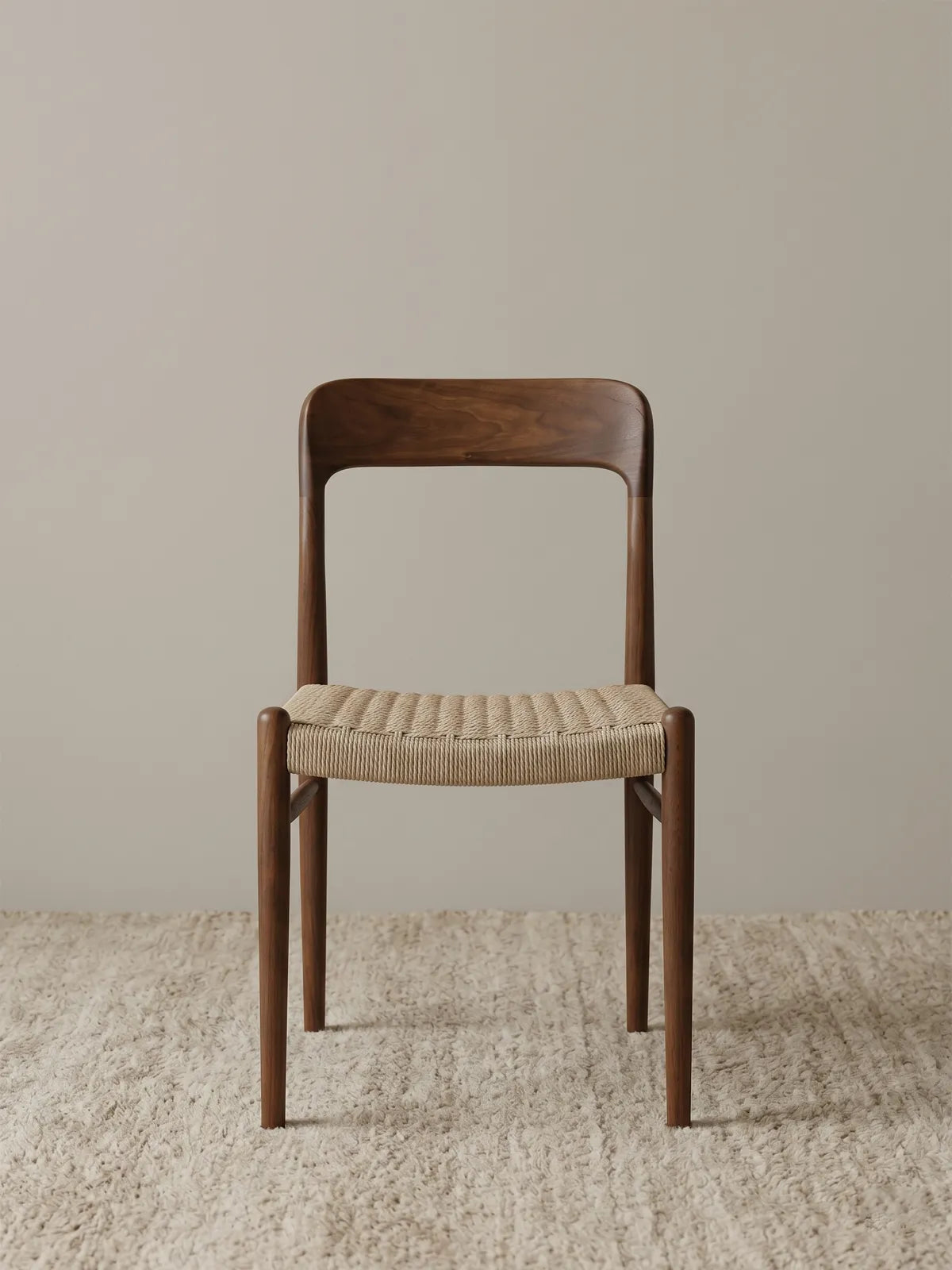 Orin woven cord dining chair in solid American black walnut, front view on neutral rug