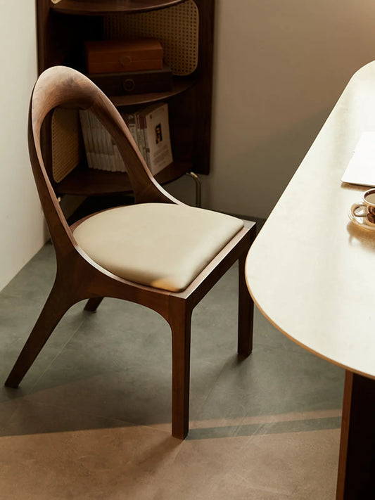 Side profile of the Oryn dining chair showing the rear leg splay and arching backrest curve.