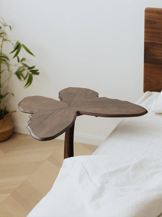 The Papillon walnut accent table utilized as a unique bedside table, highlighting its butterfly-shaped silhouette.