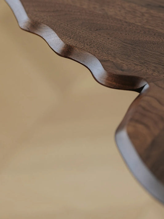 Detailed shot of the hand-finished scalloped edges and rich natural wood grain of the Papillon walnut tabletop.