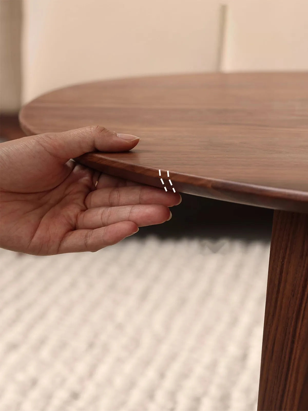Hand touching the smooth, beveled edge of The Pebble Nesting Coffee Table, highlighting the premium wood finish.