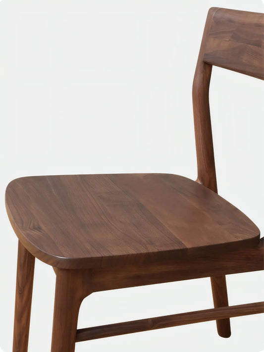 Detail of the Riven dining chair contoured solid walnut seat with softened edges and visible grain pattern