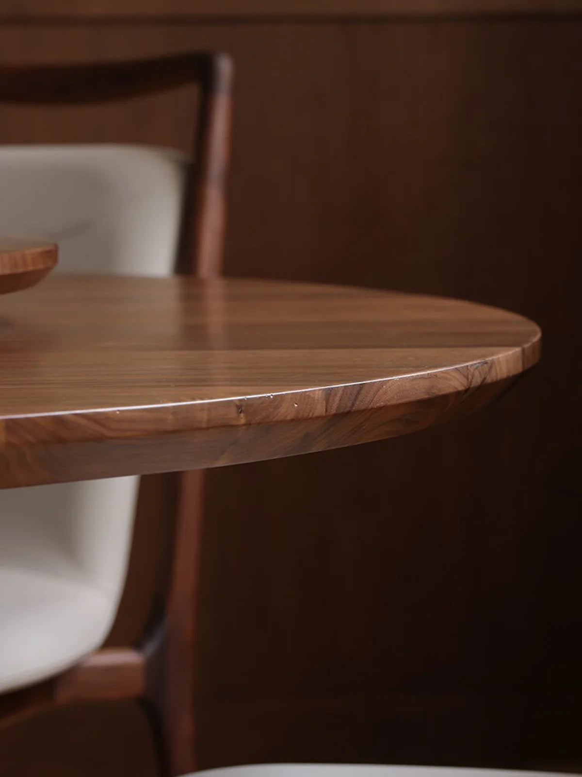 Detail view of the walnut dining table edge, showing the softly rounded profile and natural wood grain.