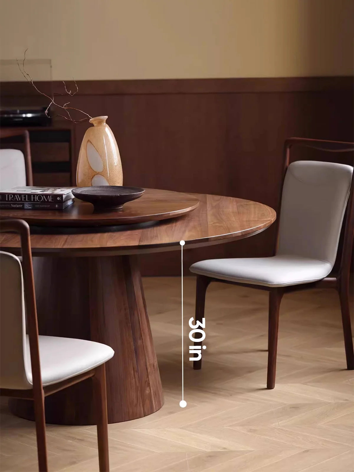 Side view of the dark walnut round dining table showing a 30-inch table height, paired with light gray upholstered chairs and a central lazy Susan.