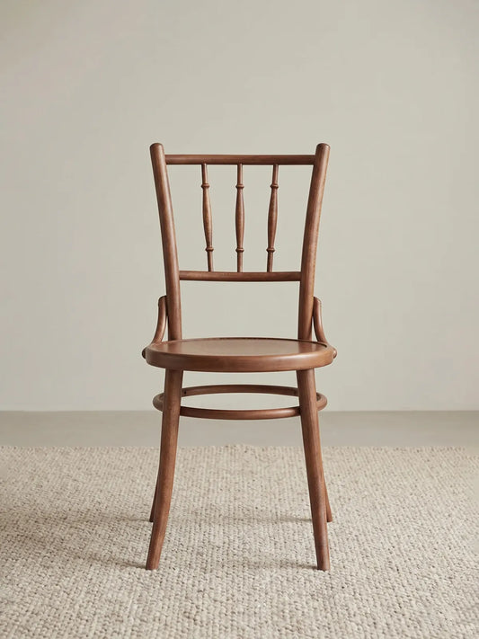 Salo spindle back dining chair in solid walnut, front view showing turned bobbin spindles, round seat, and splayed legs on a neutral rug