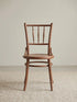 Salo spindle back dining chair in solid walnut, front view showing turned bobbin spindles, round seat, and splayed legs on a neutral rug