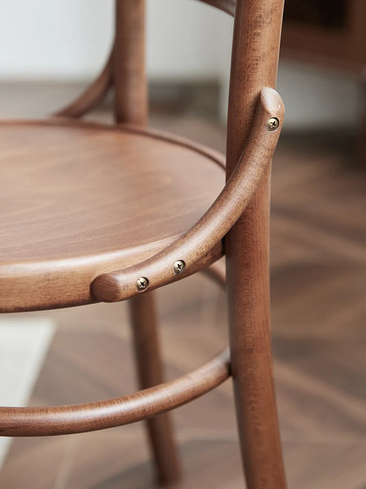 Detail of brass-toned fasteners and steam-bent hoop seat ring joinery on the Salo walnut dining chair