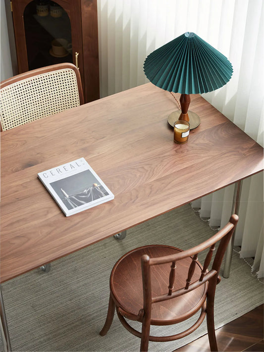 Overhead view of the Salo chair tucked under a walnut dining table with magazine and pleated lamp, showing round seat from above