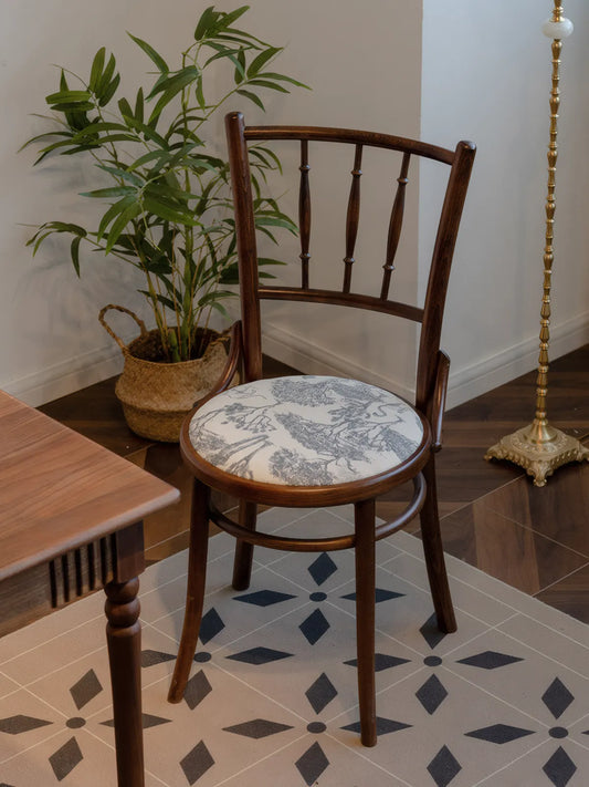 Salo walnut spindle back chair with fitted cushion beside a small table, potted palm, and brass floor lamp